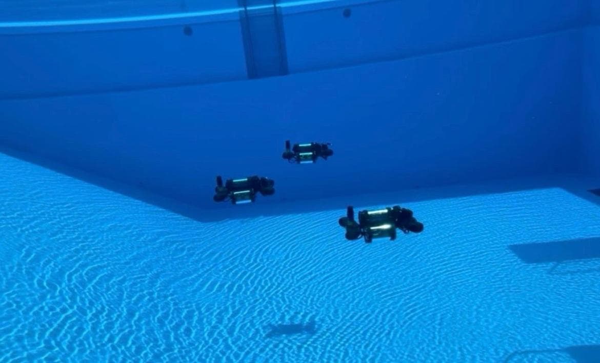 Three SWARM underwater vehicles submerged together in a pool